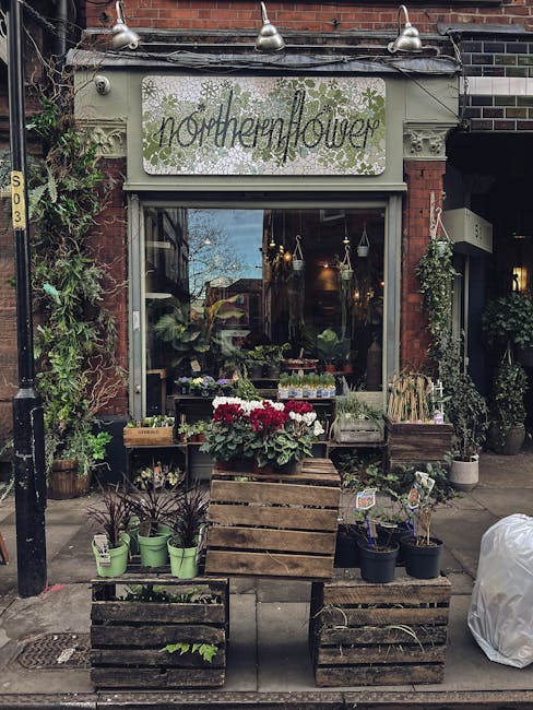 The exterior of Northern Flower, a florist shop with a white signboard displaying 'northernflower' in handwritten-style lettering with green snowflake-like decorations, situated on a brick building. T